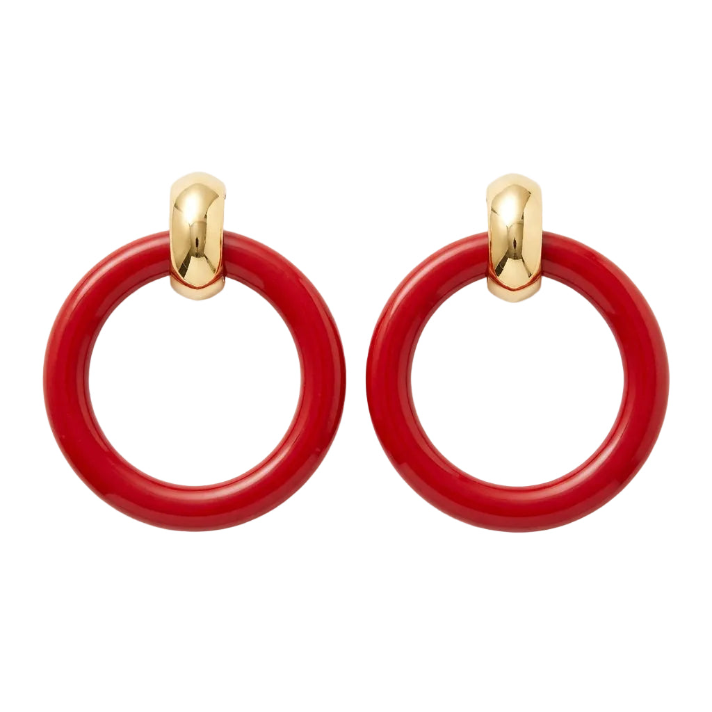 A pair of large glossy red circular hoop earrings with gold-toned posts, displayed on a small tan card against a light neutral background.